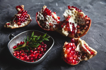 Food photo of red ripe pomegranate pieces in bowl on the gray table with copy space. Healthy food
