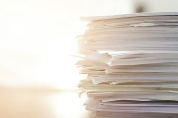 Paper stack on desk related to business functions. Paper-related work on the table.