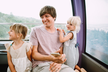 Young father with two little daughters in the cabin of a Ferris wheel in Tbilisi