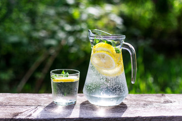 fresh lemonade and a glass on wooden old table against a backdrop of green grass