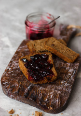 Toast with jam on a cutting board on grey table. Top view