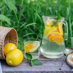 fresh lemonade and a glass on wooden old table against a backdrop of green grass