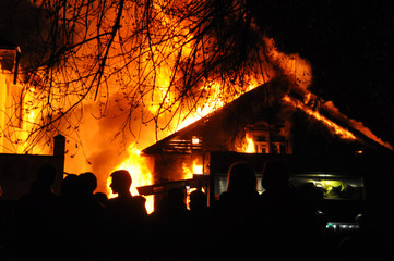 People looking an old Wooden house burning