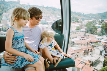 Fototapeta na wymiar father with daughters sitting in a cable car in Tbilisi