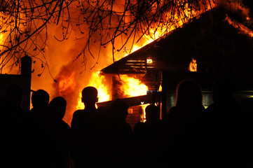 People looking an old Wooden house burning