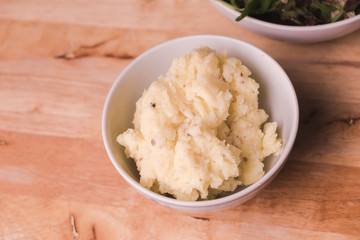 Mashed potatoes in bowl isolated on wooden background.