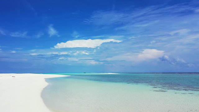 A long white beach on the left unter a beautiful ksy in the turquoise blue Sea in the Dominican Republic. Static, wide angle
