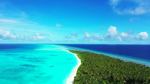 Aerial view above a tropical island with some palm trees on it. In the turquoise sea in Bali. Under a blue sky. Truck left flying above the island.