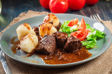 Pork meat stew served with potatoes and vegetable salad