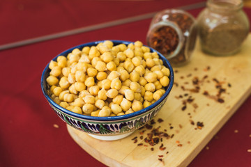 Yellow chickpeas lie in an oriental plate on a wooden spice board