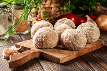 Raw meatballs rolled in a crispy bun prepared for baking