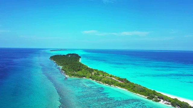 Aerial view of a tropical island in turquoise, green and blue water in Bali. Truck right, pan left