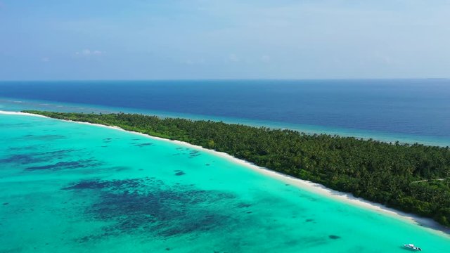Aerial view of a tropical island that leads vertically from right to left. Turquoise water in the foreground and blue water in the background. a blue sky above Bali