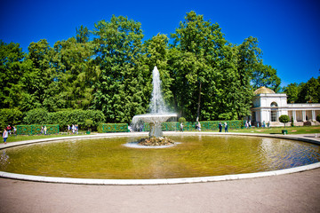 fountain on the lake on a background of green park under a blue sky