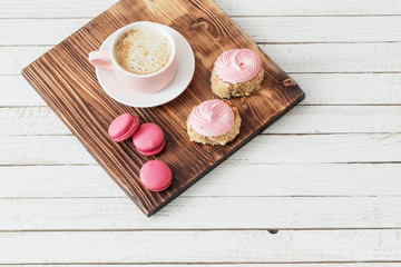 cup of coffee with cakes on white wooden background