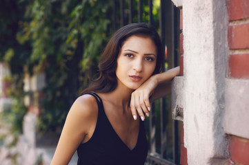 Obraz premium Open portrait of a young beautiful girl in the city . Woman wearing elegant black dress