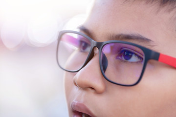 Portrait young  boy wearing glasses looking throw window on blur background .