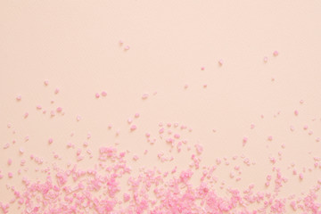 Spa therapy. Pink bath salt crystals scattered over peach surface. Abstract background. Copy space.