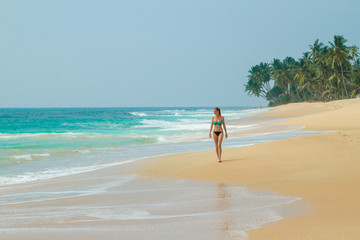 The girl is walking along the beach