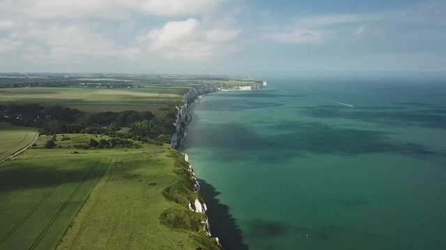 Flying over the edge of a cliff in Normandy in June, from the sea to the flax fields // left travelling