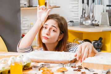 Housewife routine. Portrait of exhausted lady sitting in kitchen, hands covered with flour, waiting...