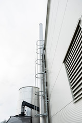 Chimney sweep cleaning a chimney standing balanced on the apex of a house roof lowering equipment down the flue