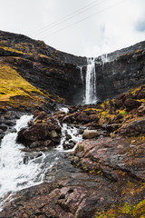 Fossa, the largest waterfall on the Faroe Islands, as seen during early spring with snow-covered mountain peaks and lush greens (Faroe Islands, Denmark, Europe) 