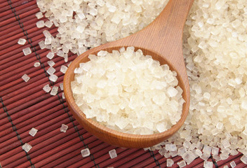 Spoon and sugar on red bamboo background