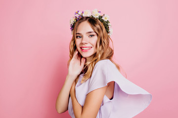 Romantic girl with lightly-tanned skin weating flower wreath. Indoor photo of adorable caucasian female model with short wavy hair.