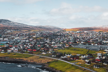 Aerial shot of the Faroese town Torshavn as taken during a helicopter flight on an early spring morning with snow-covered mountain peaks (Faroe Islands, Denmark, Europe)