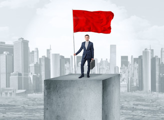 Handsome businessman on the top of the city with red flag
