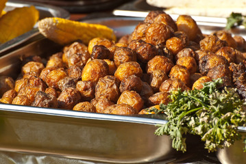 Roast potatoes in a large pan. Delicious food at the festival. Field kitchen at the hearth.