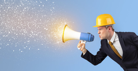 Fototapeta premium Young architect constructor yelling with megaphone and sparkling sounds 