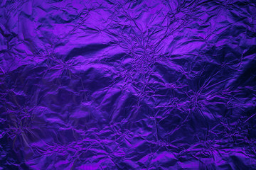 Violet purple deformed background made of illuminated foil