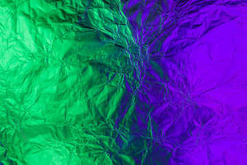 Violet green deformed background made of neon lights foil. Trendy duotone texture
