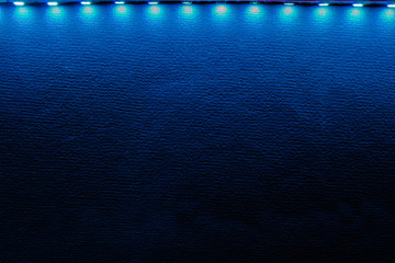 Backlit background of blue led strip lights and reflections on black