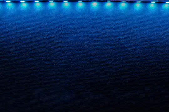 Backlit background of blue led strip lights and reflections on black