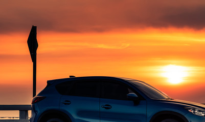 Side view of blue SUV car with sport and modern design parked on concrete road at sunset. Hybrid...