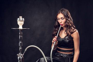 girl smokes hookah / beautiful glamorous girl in black dress smokes a hookah