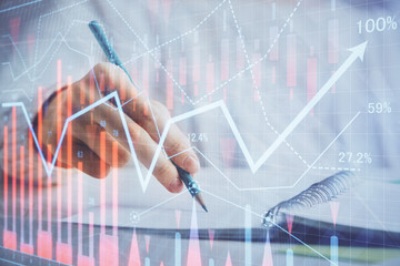 Financial forex graph displayed on hands taking notes background. Concept of research. Double exposure