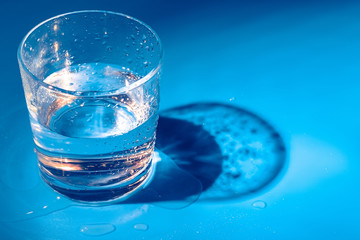 A glass with water drops  on a dark blue background close up