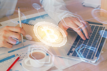 Crypto currency theme hologram with businessman working on computer on background. Concept of blockchain. Double exposure.
