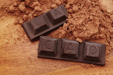 Chocolate bars with word cacao and cacao powder on wooden background