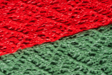 Red and green knitted woolen sweater texture. Colorful textured background. Laid diagonally horizontal image.