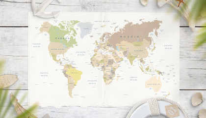 The map of the world is surrounded by symbols from the sea in the shade of palm trees. Top view, flat lay. World travel concept.