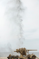 Howitzer on the sand with bomb explosion