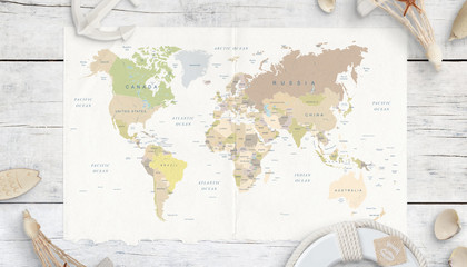 World map on white wooden table. Travel concept. Map surrounded with shells, anchor, lifebelt and souvenirs. Top view.