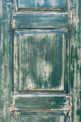 Detail eines alten, verwitterten, grünen Fensterladen im Hochformat