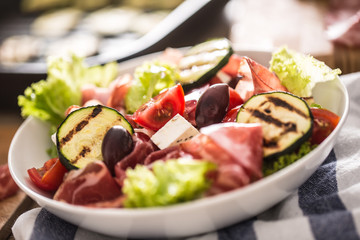 Fresh lettuce salad with grilled zucchini coppa di parma ham feta cheese olives tomatoes and olive...