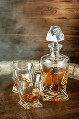 A bottle of cognac and glass on a brown wooden background. Brandy